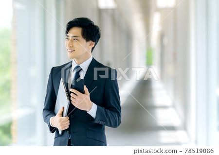 A businessman in a suit holding a smartphone in an office 78519086