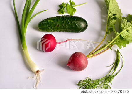 Red radish fruits with tops, green onions and cucumber on white. 78520150