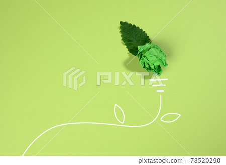 a crumpled sheet of paper and a green leaf on a green background, the shape of a light bulb. Energy saving concept, new creative idea 78520290