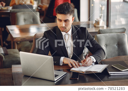Stylish businessman working in a cafe and use the laptop Stylish businessman working in a cafe and use the laptop 78521283