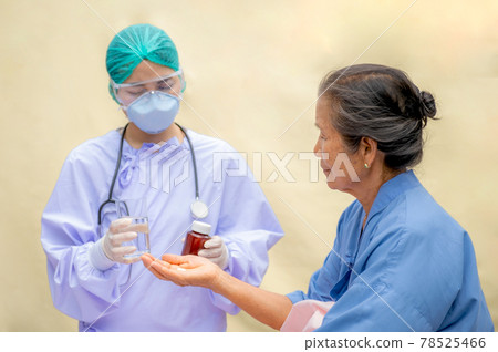 The elderly patient in bed takes the medicine that the doctor has given. Doctors wearing face masks due to COVID outbreak The elderly patient in bed takes the medicine that the doctor has given. Doctors wearing face masks due to COVID outbreak 78525466