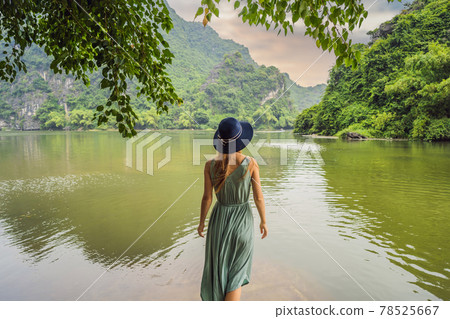 Woman tourist in Trang An Scenic Landscape Complex in Ninh Binh Province, Vietnam A UNESCO World Heritage Site. Resumption of tourism in Vietnam after quarantine Coronovirus COVID 19 78525667