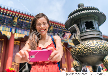 Tourist using mobile phone taking photos of old temple bronze sculpture in Beijing, china. Asia tourism travel. People during vacation 78525852
