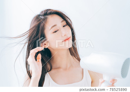 婦女用吹風機烘乾她的頭髮。 78525890