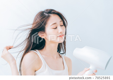 婦女用吹風機烘乾她的頭髮。 78525891