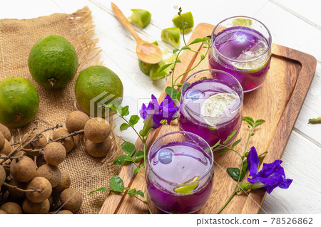 Glass of lemon juice, Pea flowers and Longan on white wooden table 78526862