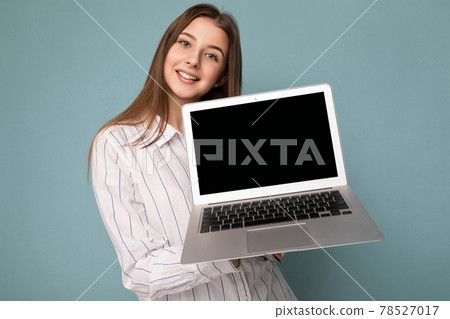 Close-up portrait of Beautiful smiling young woman holding netbook computer looking at camera Close-up portrait of Beautiful smiling young woman holding netbook computer looking at camera 78527017