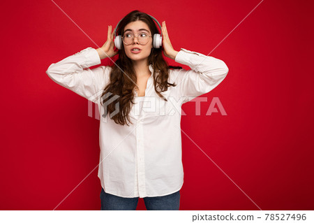 Attractive young brunette female person wearing white shirt and optical glasses isolated over red 78527496