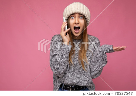 Closeup portrait of Attractive amazed young blonde woman wearing casual grey sweater and beige hat 78527547