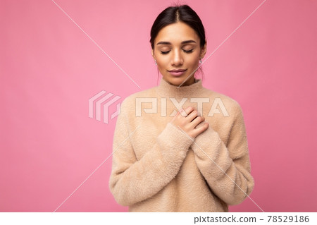 Portrait of young positive cute pretty brunette woman with sincere emotions wearing beige sweater 78529186