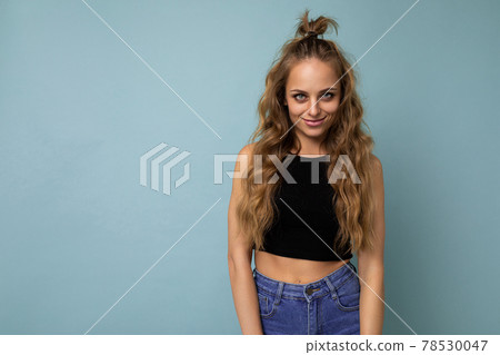 Young beautiful blond woman wearing black top t-shirt looking at camera. Positive female shows Young beautiful blond woman wearing black top t-shirt looking at camera. Positive female shows 78530047