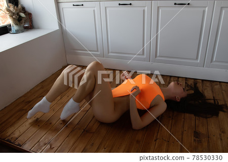 Alluring woman in bodysuit lying gracefully on floor Alluring woman in bodysuit lying gracefully on floor 78530330