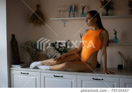 Voluptuous hot woman in bodysuit lying on kitchen unit Voluptuous hot woman in bodysuit lying on kitchen unit 78530487