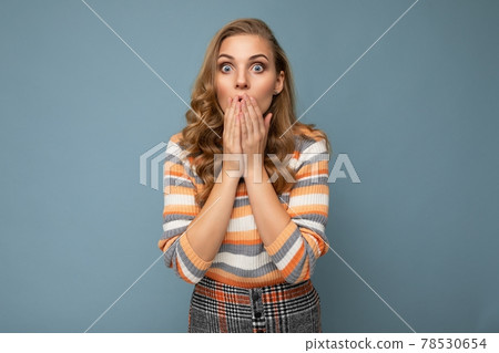 Portrait of young shocked blonde beautiful curly woman with sincere emotions wearing striped sweater 78530654