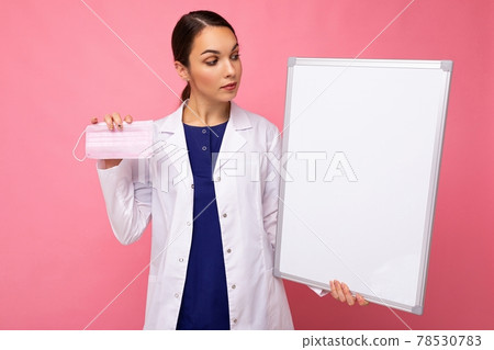 Woman doctor in a white medical coat holding blank board with copy space for text and protective Woman doctor in a white medical coat holding blank board with copy space for text and protective 78530783