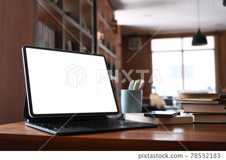 Close up view of mock up computer tablet with blank screen and books on wooden desk in library. Close up view of mock up computer tablet with blank screen and books on wooden desk in library. 78532183