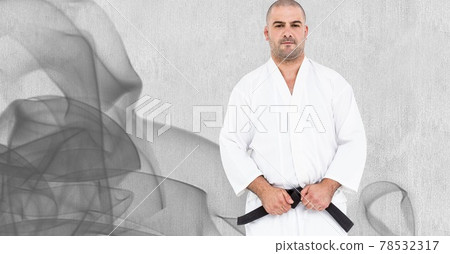 Composition of caucasian male martial artist with black belt over trails of smoke o grey background 78532317