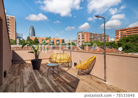 Bright terrace with yellow exterior chairs, wooden floor, shower and amazing view of area of Poblenou, old industrial district converted into new modern neighbourhood in Barcelona, Spain Bright terrace with yellow exterior chairs, wooden floor, shower and amazing view of area of Poblenou, old industrial district converted into new modern neighbourhood in Barcelona, Spain 78533848