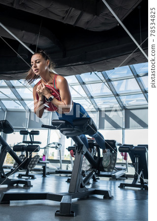 Young woman doing hyperextension with weight plate at gym Young woman doing hyperextension with weight plate at gym 78534825