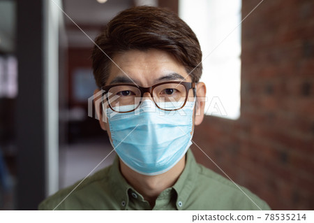Portrait of asian businessman wearing face mask in office looking to camera Portrait of asian businessman wearing face mask in office looking to camera 78535214