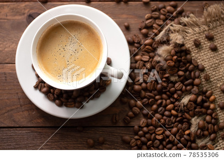 Cup of coffee on wooden table with roasted coffee beans on wooden background. 78535306