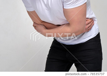 A man in a white T-shirt holds on to his stomach. Concept of poisoning, muscle spasm. A man in a white T-shirt holds on to his stomach. Concept of poisoning, muscle spasm. 78535737