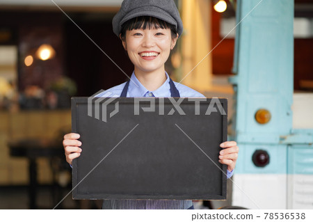 Female clerk holding a message board in front of the kitchen car 78536538