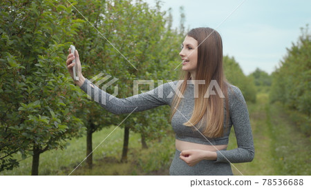 Joyful fitness woman during live stream broadcasting. A modern sports woman takes pictures on the nature smartphone, recording a video blog. Sports video vlog. Video Blog athlete. Girl blogger Joyful fitness woman during live stream broadcasting. A modern sports woman takes pictures on the nature smartphone, recording a video blog. Sports video vlog. Video Blog athlete. Girl blogger 78536688