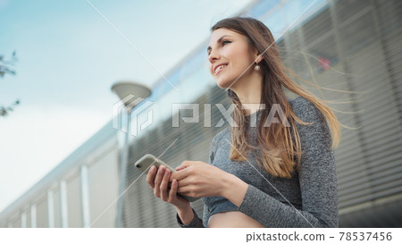 Close-up Of A Young Beautiful Sports Fitness Girl Holding A Smartphone In The Hands, Using A Fitness App. Modern City Shooting On the Street. Portrait woman looking at smartphone while running outdoor Close-up Of A Young Beautiful Sports Fitness Girl Holding A Smartphone In The Hands, Using A Fitness App. Modern City Shooting On the Street. Portrait woman looking at smartphone while running outdoor 78537456