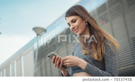 Close-up Of A Young Beautiful Sports Fitness Girl Holding A Smartphone In The Hands, Using A Fitness App. Modern City Shooting On the Street. Portrait woman looking at smartphone while running outdoor Close-up Of A Young Beautiful Sports Fitness Girl Holding A Smartphone In The Hands, Using A Fitness App. Modern City Shooting On the Street. Portrait woman looking at smartphone while running outdoor 78537458