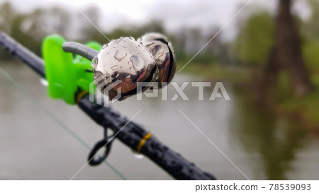 Silver fishing bells are worn on a fishing rod while fishing. Bite-call signal, at the tip of the rod. A bite alarm will alert you to a bite. Fishing tackle close-up. Silver fishing bells are worn on a fishing rod while fishing. Bite-call signal, at the tip of the rod. A bite alarm will alert you to a bite. Fishing tackle close-up. 78539093
