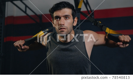 Muscular man during exercise training workout bodyweight with suspension straps TRX 78540813
