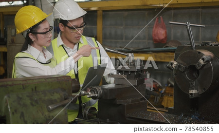 mechanical engineer woman and operation man wearing uniform hardhat and goggles safety working on workshop metal lathe mechanical engineer woman and operation man wearing uniform hardhat and goggles safety working on workshop metal lathe 78540855