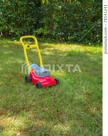 Push lawn mower toy on the grass in a garden . No people Push lawn mower toy on the grass in a garden . No people 78541241