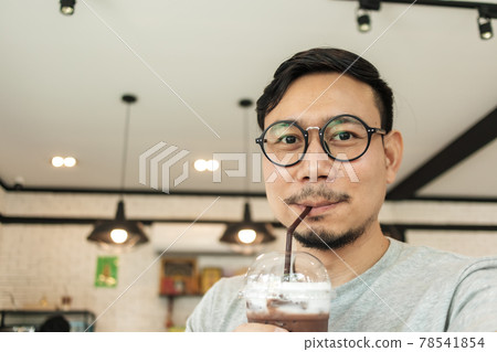 Happy man drinking iced cocoa in the cafe. 78541854