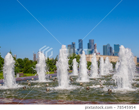 Jets of fountains against the backdrop of skyscrapers and a cloudless blue sky. Jets of fountains against the backdrop of skyscrapers and a cloudless blue sky. 78545954
