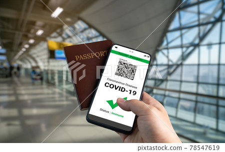 Traveler holds vaccine passport certificate to show COVID 19 vaccination status Traveler holds vaccine passport certificate to show COVID 19 vaccination status 78547619