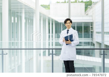A young doctor in a white coat looking at a medical record at the hospital A young doctor in a white coat looking at a medical record at the hospital 78547872