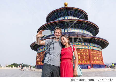 Happy couple travelers taking selfie picture together at temple of heaven during china summer travel. Young multiracial people using phone photography app for photos 78548212