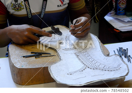 PUTRAJAYA, MALAYSIA -JANUARY 29, 2017: A man using his fine skill to made wayang kulit character. Waang kulit is a traditional Malaysian Malay shadow performance made from hard animal leather. PUTRAJAYA, MALAYSIA -JANUARY 29, 2017: A man using his fine skill to made wayang kulit character. Waang kulit is a traditional Malaysian Malay shadow performance made from hard animal leather. 78548502