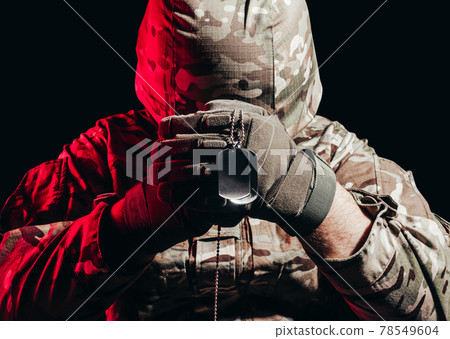 Soldier in uniform and helmet holding army necklace. 78549604