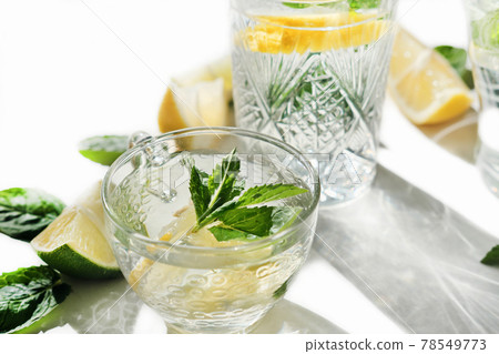 fresh lemon and mint drink in a glass cup. summer cold infused water for freshness. lime and lemon slices. healthy drinks for kids party fresh lemon and mint drink in a glass cup. summer cold infused water for freshness. lime and lemon slices. healthy drinks for kids party 78549773