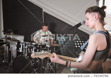 rock band rehearsal in a studio. audio sound check. teen boy playing drums and female guitarist with an instrument. music or song performance rock band rehearsal in a studio. audio sound check. teen boy playing drums and female guitarist with an instrument. music or song performance 78549790