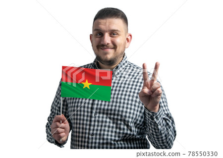 White guy holding a flag of Burkina Faso and shows two fingers isolated on a white background 78550330