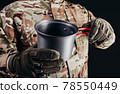 Soldier in gloves holding metal dish cup. 78550449