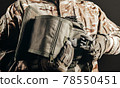 Soldier in gloves holding tactical leg bag. 78550451