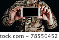 Soldier in gloves holding smartphone. 78550452
