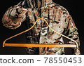 Soldier in gloves holding wooden shirt hanger. 78550453