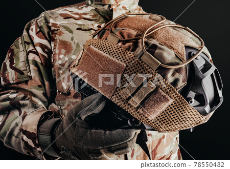 Soldier in gloves holding helmet with cover. 78550482