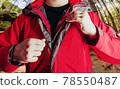 Man putting on travel hiking red jacket in woods. 78550487
